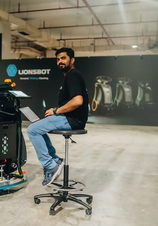 A LionsBot engineer working on a robot from a laptop in the Singapore workshop